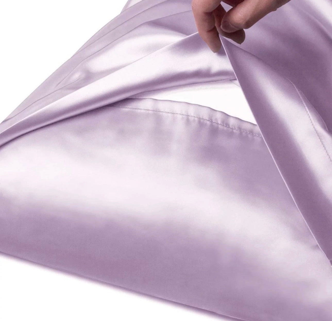 Silky purple fabric being held with a hand on a white background